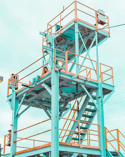 structure woman sitting on teal and yellow metal tower during daytime richmond